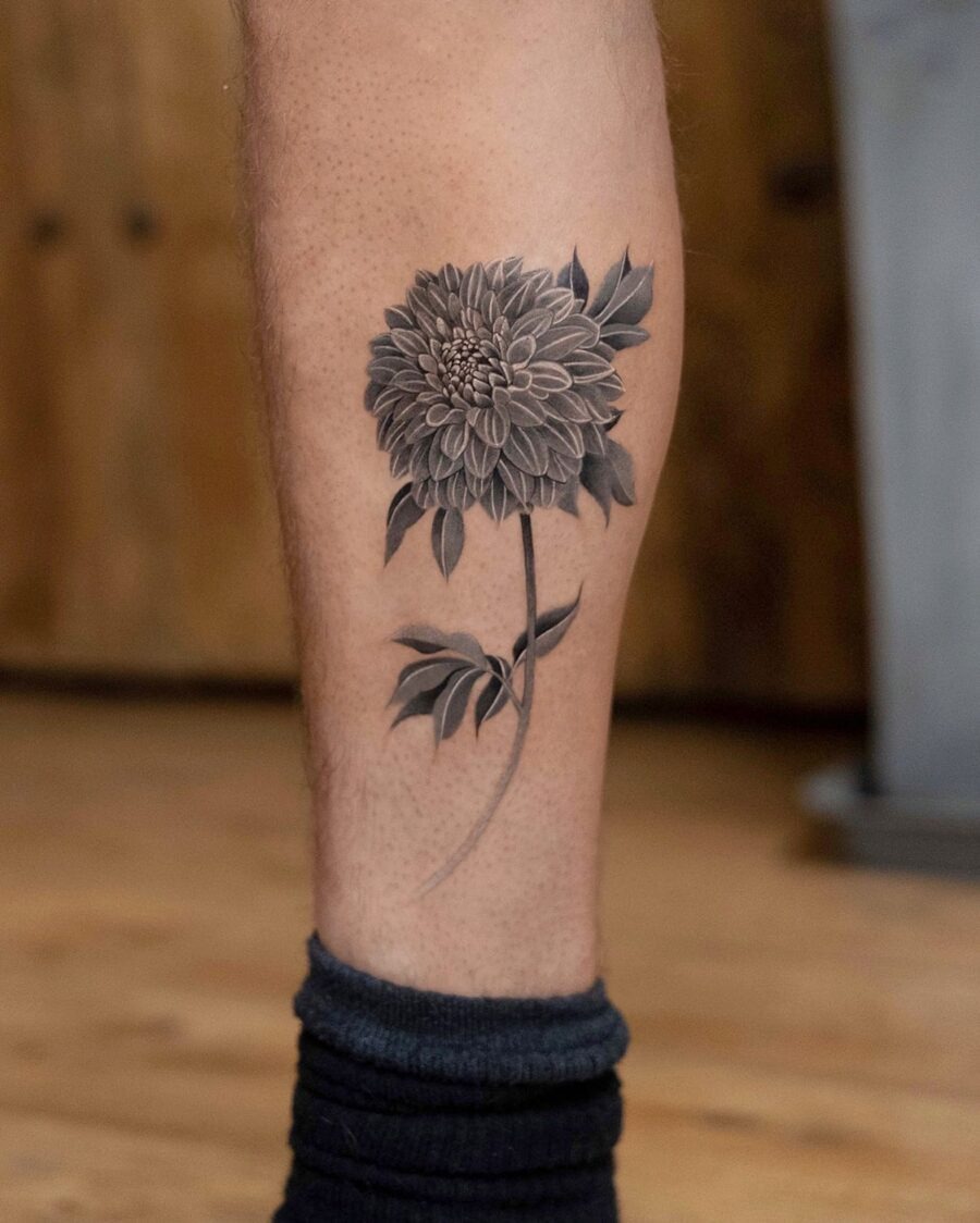 This stunning dahlia tattoo is intricately designed in shades of black and gray.