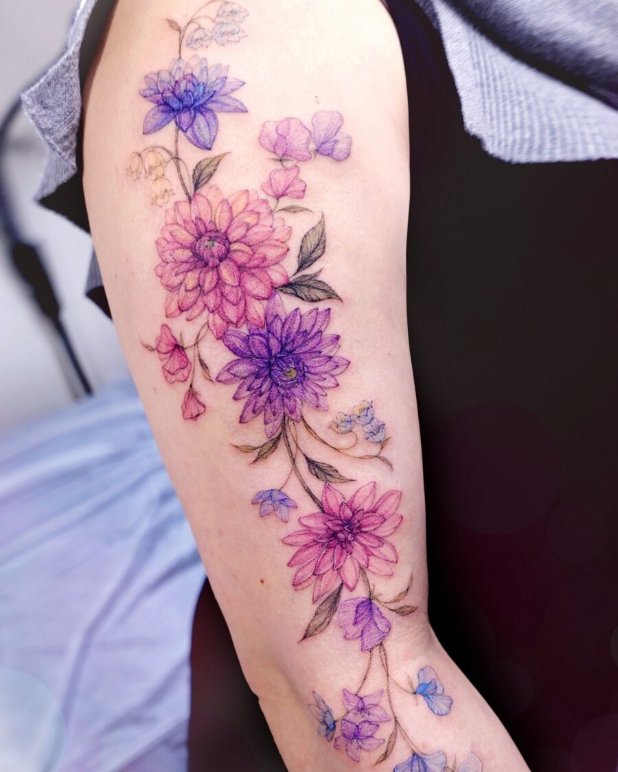 This beautiful dahlia tattoo features a blend of pink and purple hues, creating a soft and feminine vibe.