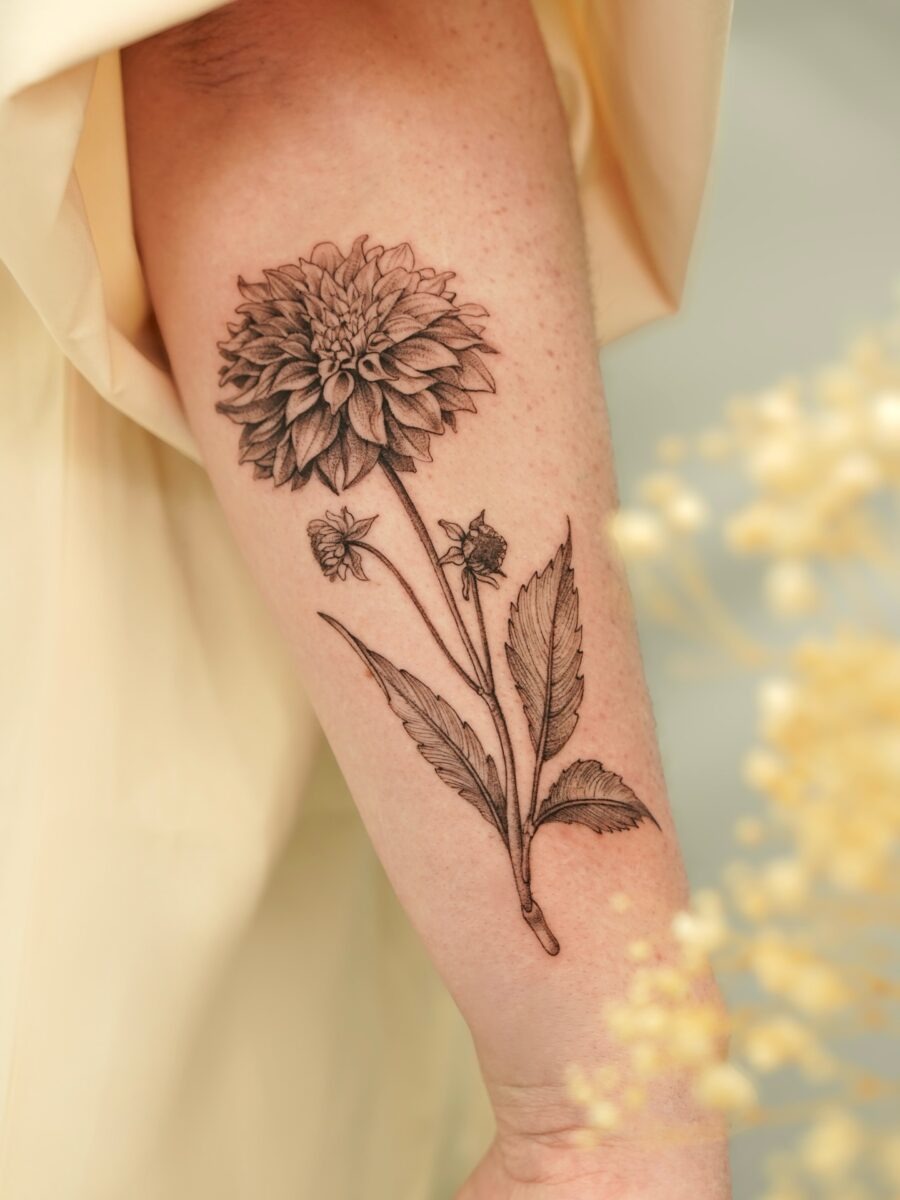 This dahlia tattoo showcases intricate details and a striking black and white design.