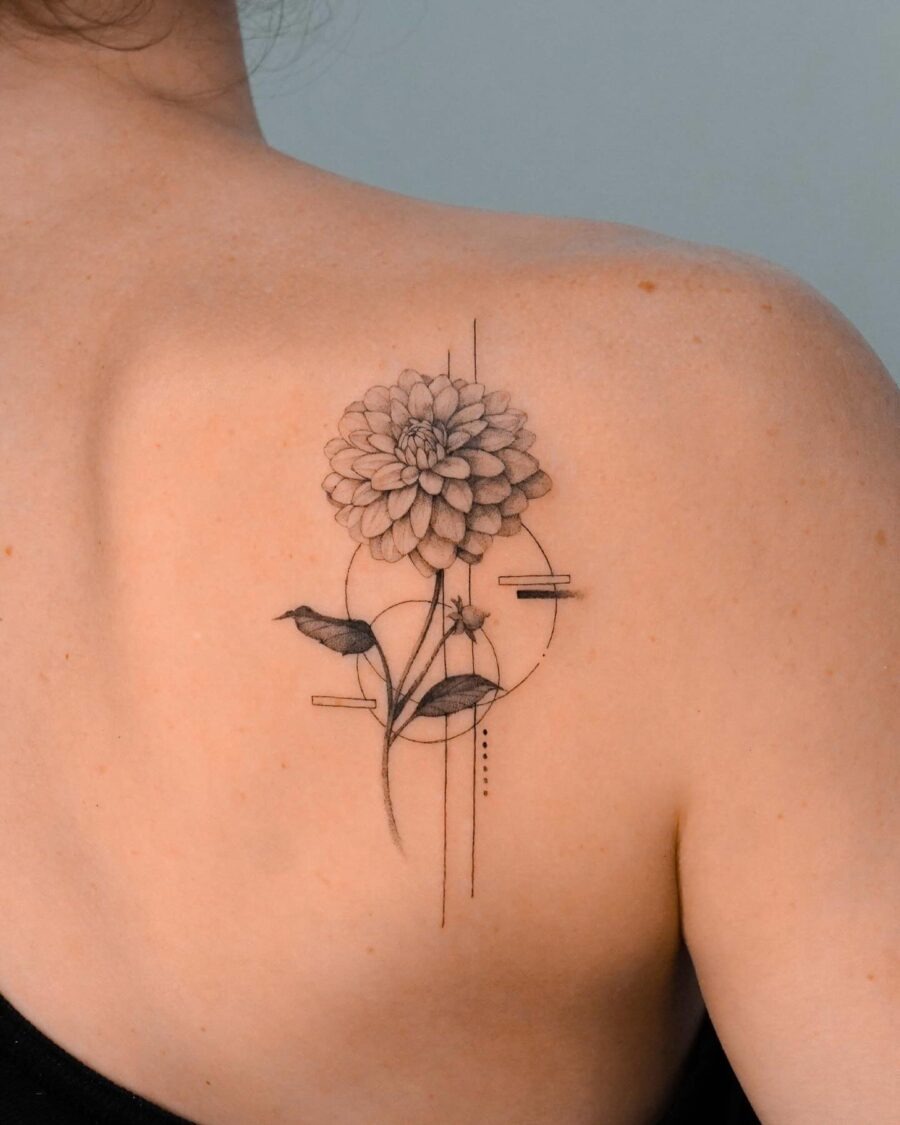 This stunning dahlia tattoo graces the back, showing soft, intricate linework.