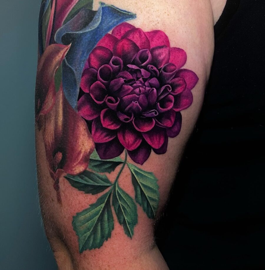 This stunning dahlia tattoo showcases rich purple tones and intricate detailing, enhancing the flower's natural beauty.