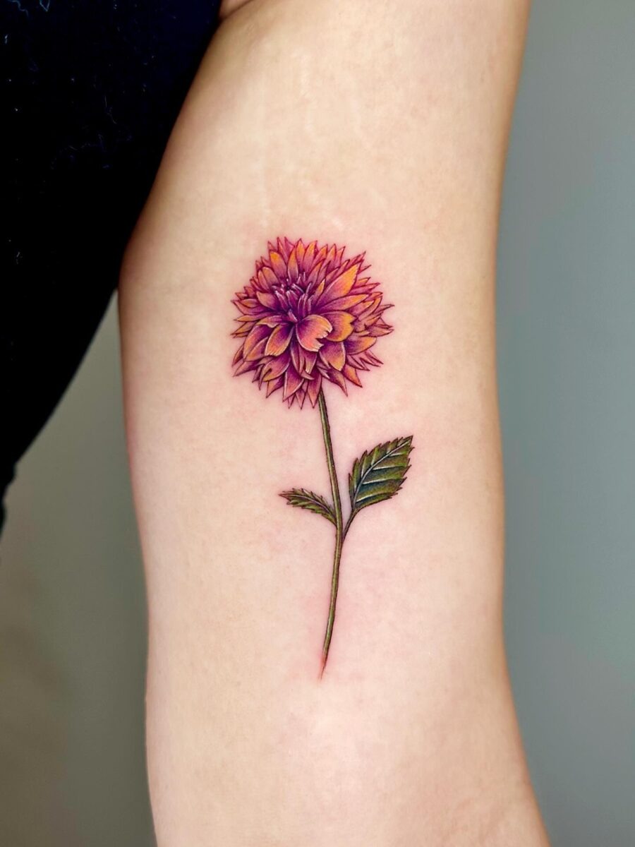 This stunning dahlia tattoo features deep red petals and intricate detailing.