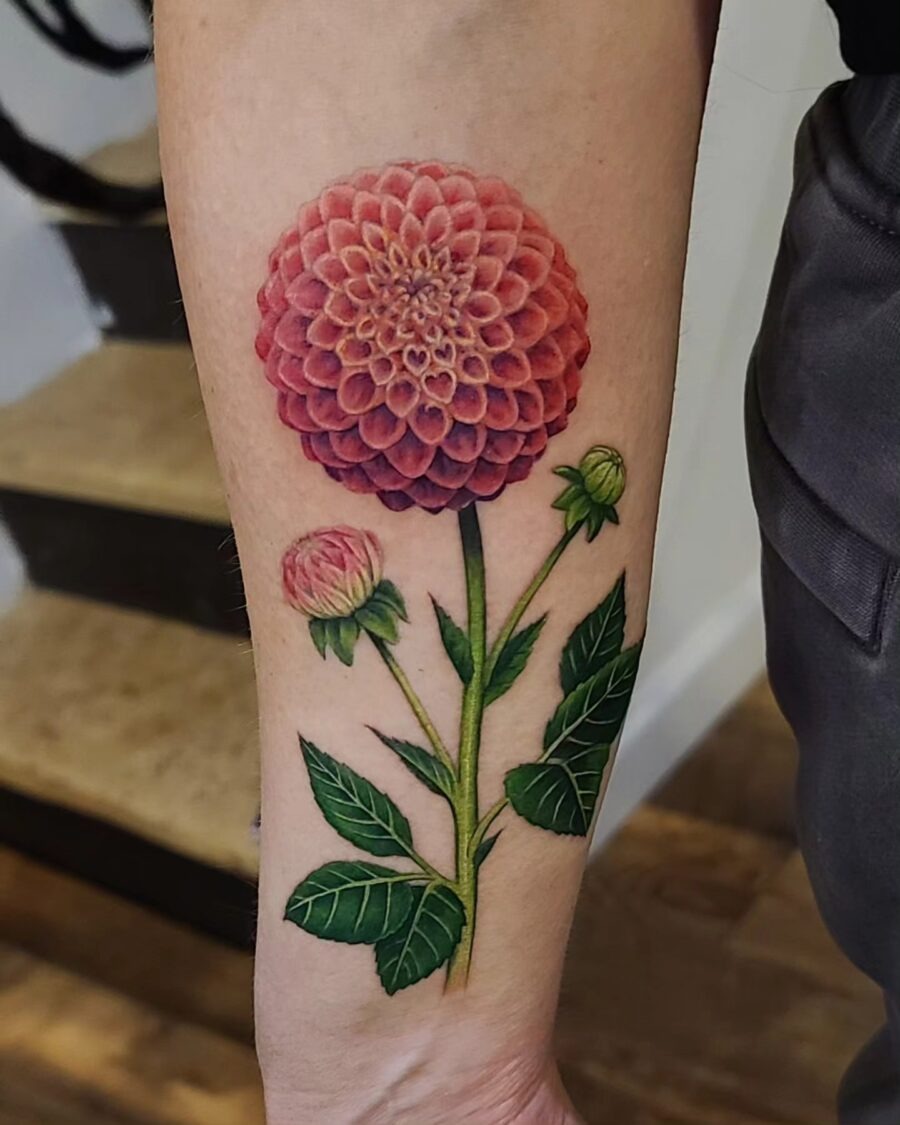 This bold dahlia tattoo showcases intricate details and a beautiful color palette.