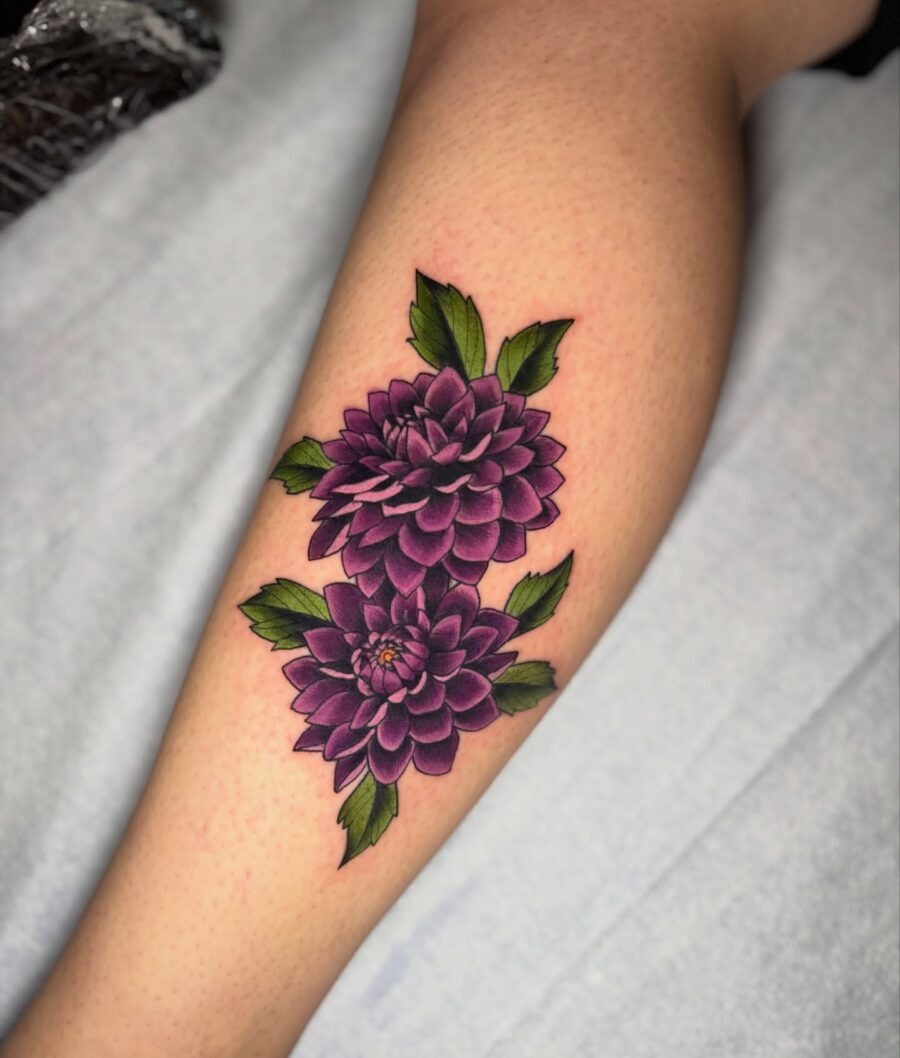 This tattoo showcases two purple dahlias beautifully blooming together.
