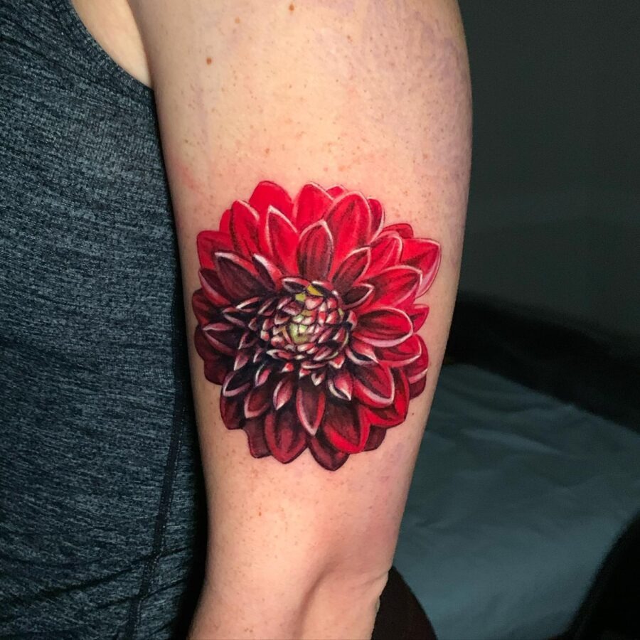 This dahlia tattoo features rich shades of red and a detailed design that captures the flower's beauty.