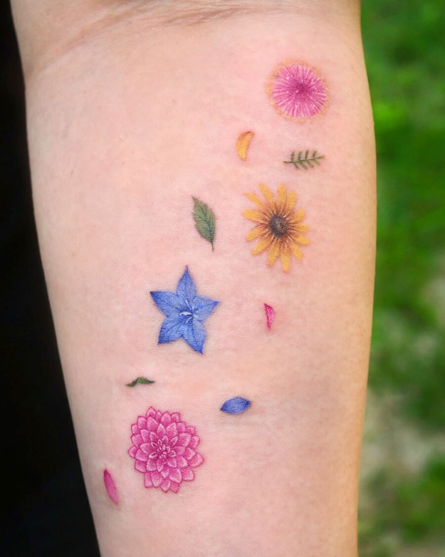 This tattoo showcases a vivid arrangement of dahlia flowers in various colors, radiating joy and creativity.