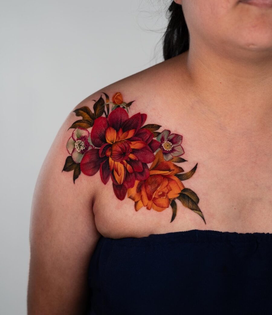 This stunning shoulder tattoo features dahlias in shades of red and orange, complemented by smaller flowers.