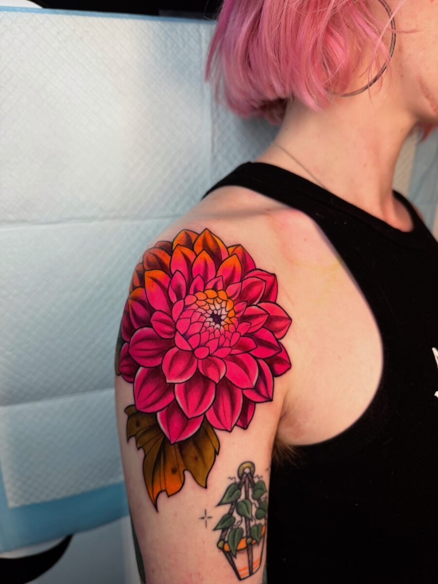 This stunning dahlia tattoo bursts with pink hues, beautifully inked on the shoulder.