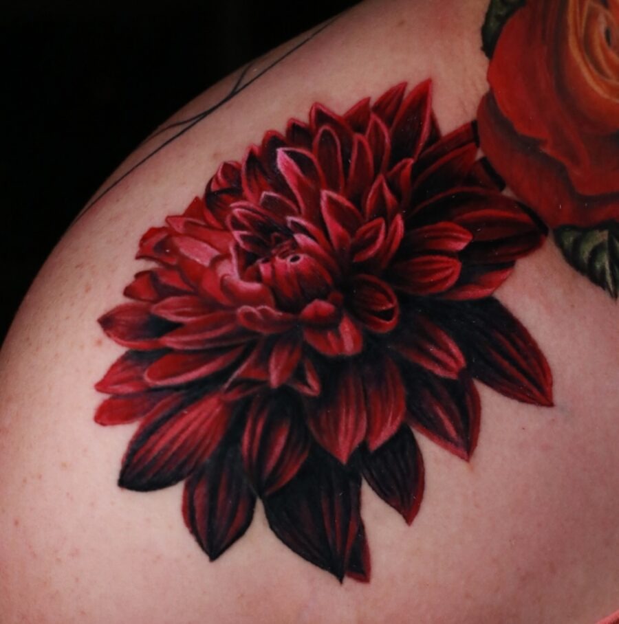 This stunning dahlia tattoo features intricate red petals with rich shading.