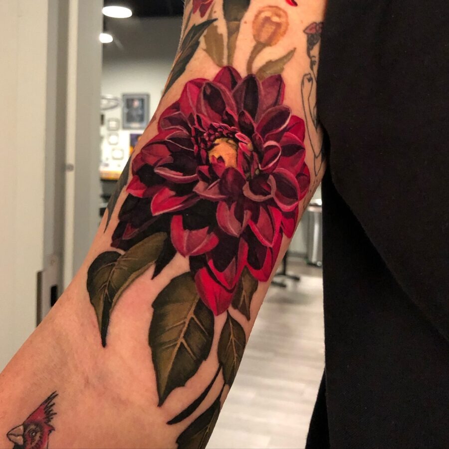 This stunning dahlia tattoo features deep red petals and intricate detailing.