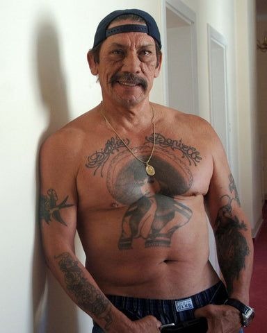 Dressed casually with a backward cap, Trejo's tattoos shine under the soft indoor lighting.