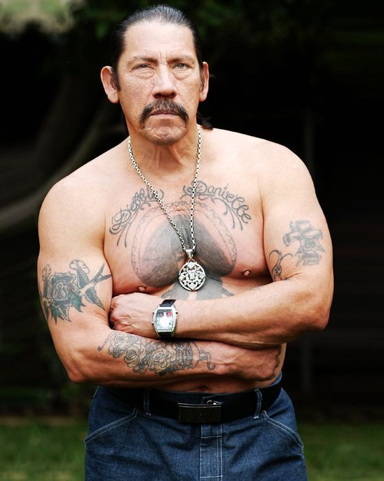 This powerful image shows Trejo standing with arms crossed, his tattoos boldly displayed against his muscular frame.