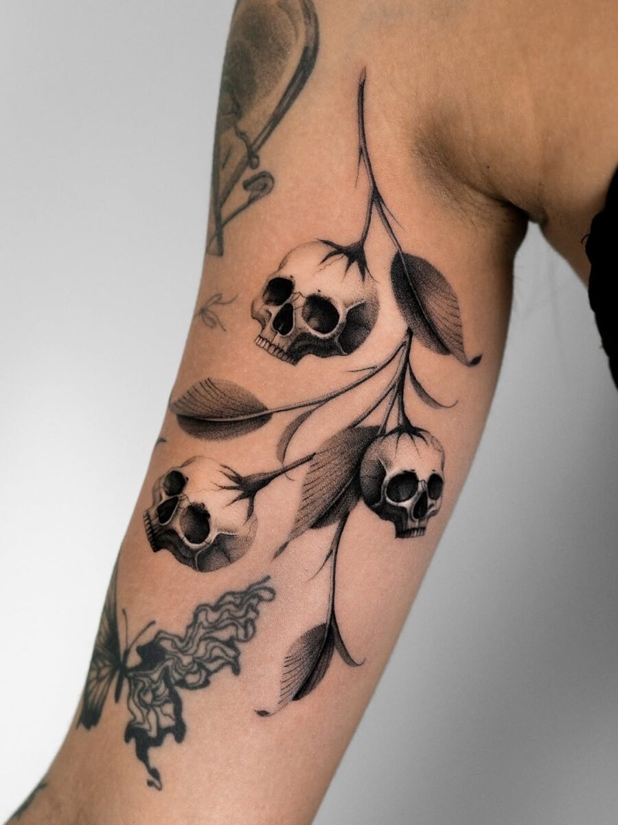 Intricate skulls interwoven with delicate foliage. Tattoo Design