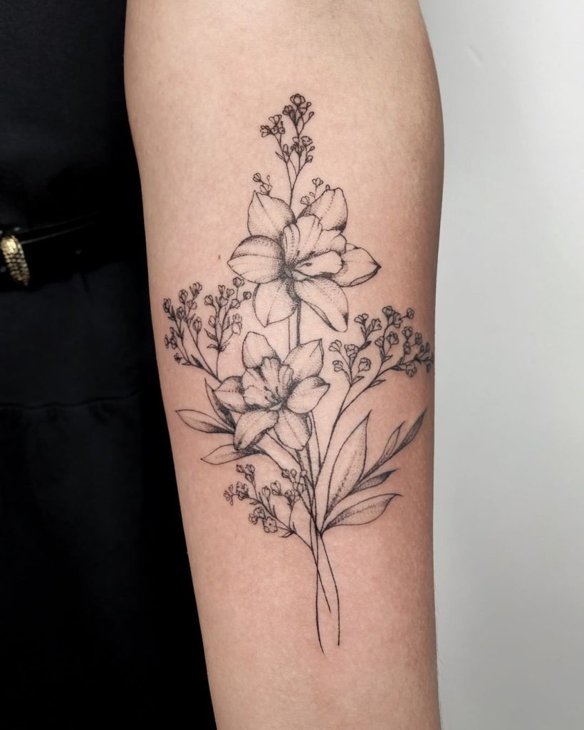 This tattoo highlights a stunning arrangement of Narcissus flowers surrounded by sprays of gypsophila (baby's breath).