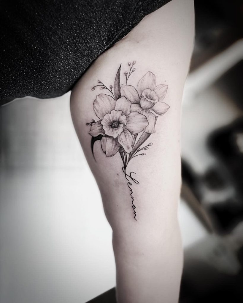 This tattoo combines a bouquet of Narcissus flowers with a custom name inscribed below.
