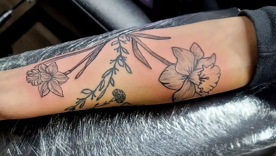This tattoo takes on a stencil-inspired look, where Narcissus blooms are paired with simple, flowing lines and leaves.