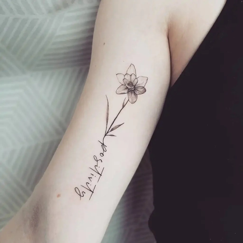 A single Narcissus flower is gracefully combined with elegant calligraphy in this tattoo, adding an extra layer of meaning to the design.
