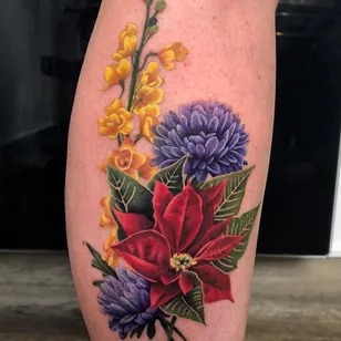This tattoo showcases a design that combines the Narcissus flower with Holly, representing both December birth flowers in one striking piece.