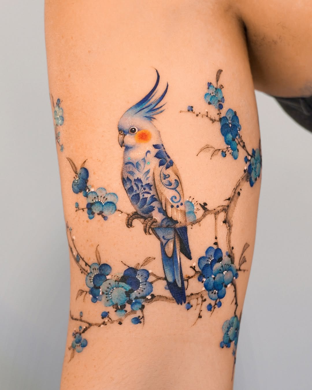 Vibrant Bird Tattoo with Floral Elements Tattoo Design