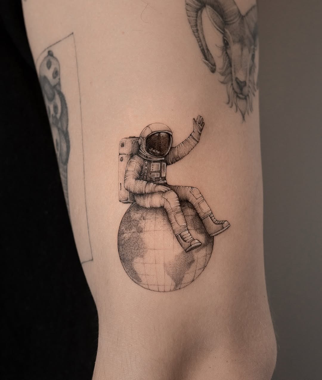 Charming astronaut tattoo resting on Earth Tattoo Design