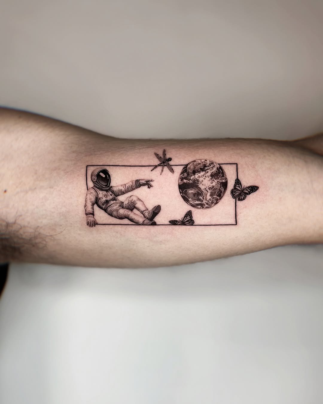 Stylish astronaut tattoo with butterflies and Earth. Tattoo Design