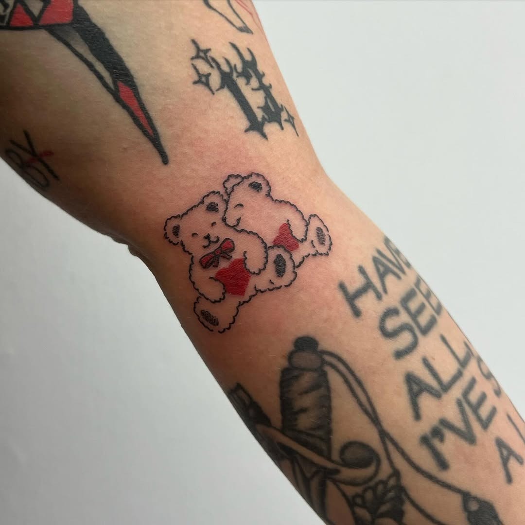This tattoo features two adorable teddy bears embracing each other, radiating a playful and loving vibe.