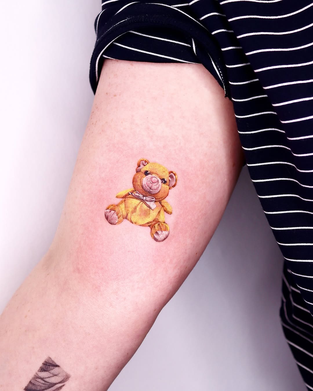This tattoo features a charming teddy bear design, exuding warmth and nostalgia.
