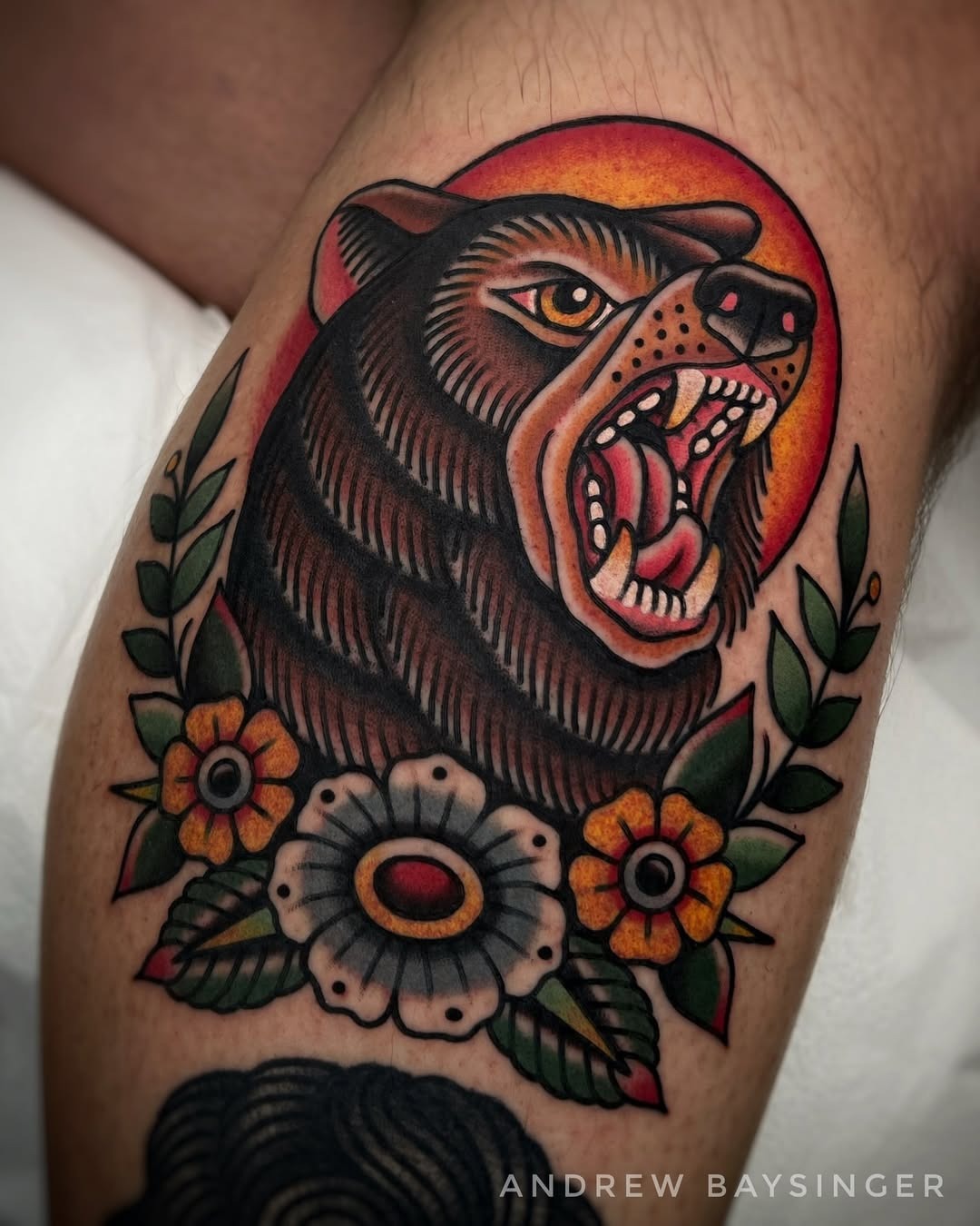 This striking bear tattoo showcases a fierce expression surrounded by flowers.