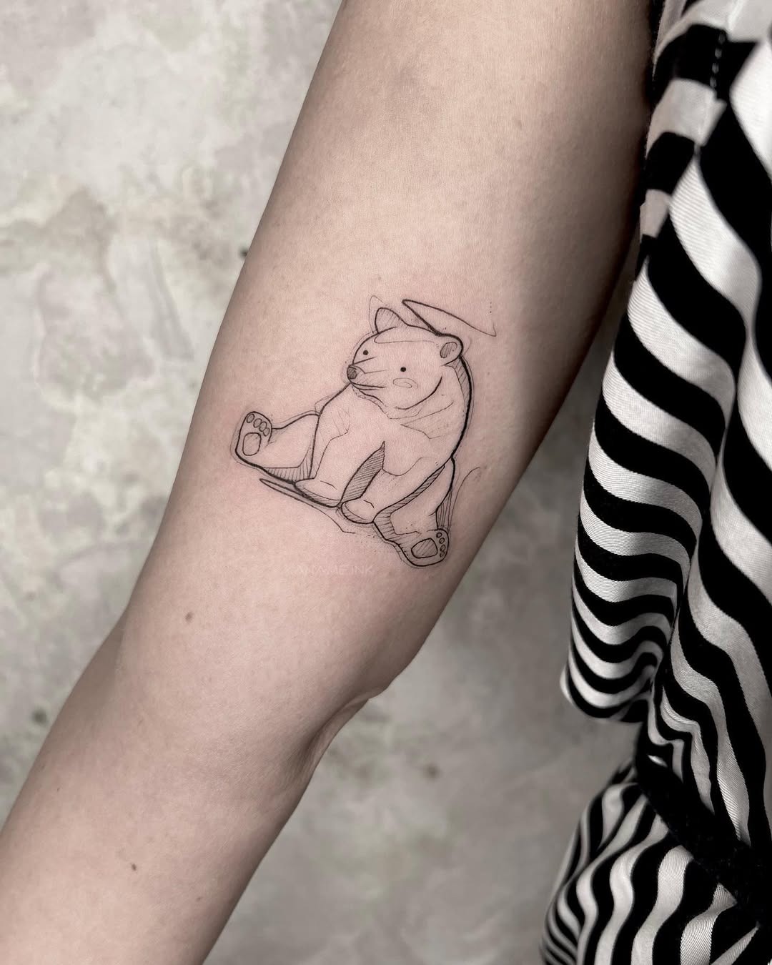 This bear tattoo features a simple and charming line art style.