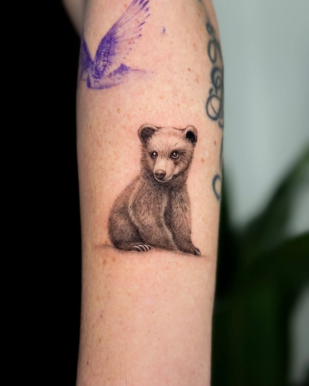 This tattoo features a cute, realistic bear cub captured in meticulous detail.