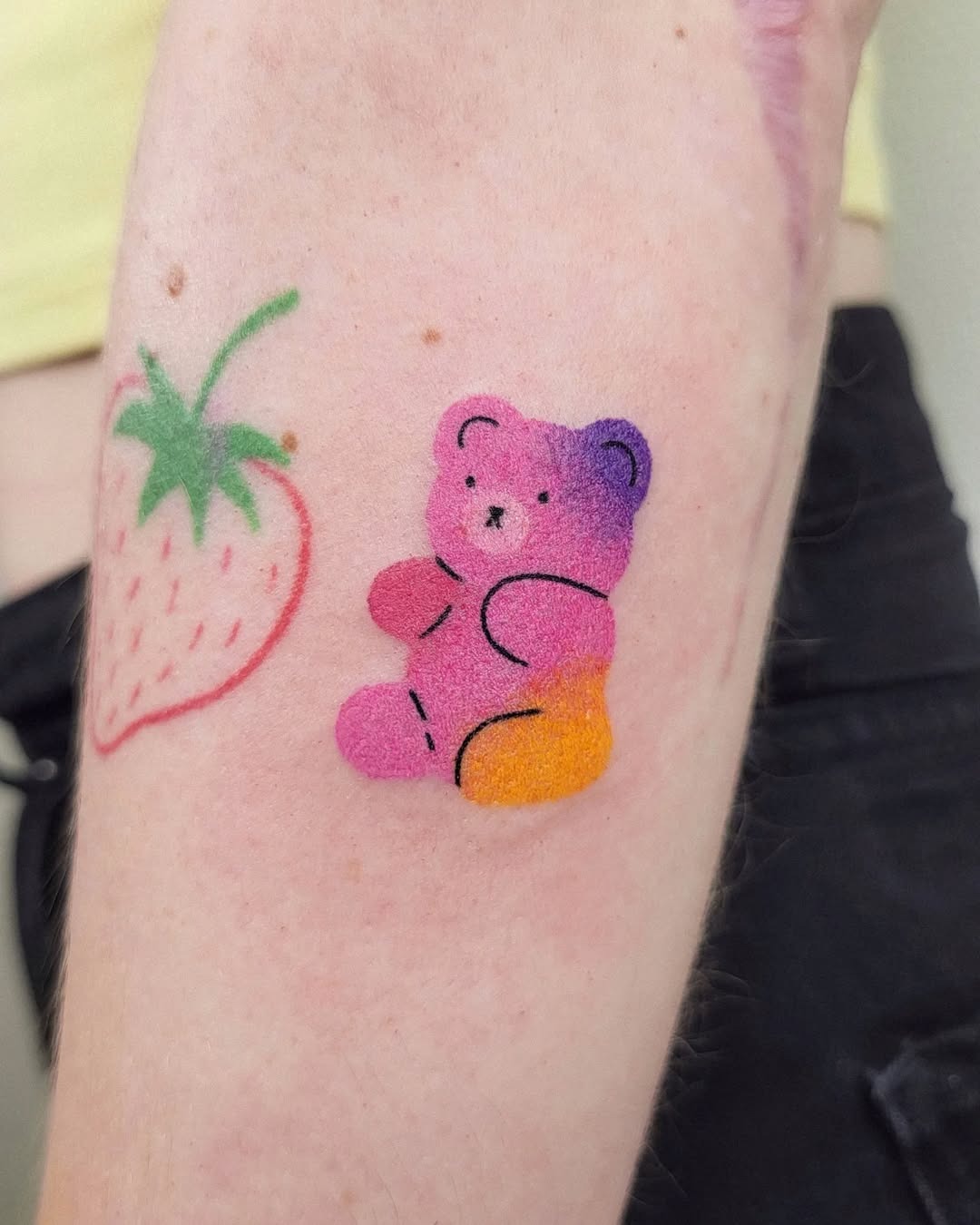 This tattoo features a cute bear in a ombre pattern that transitions from purple to orange.