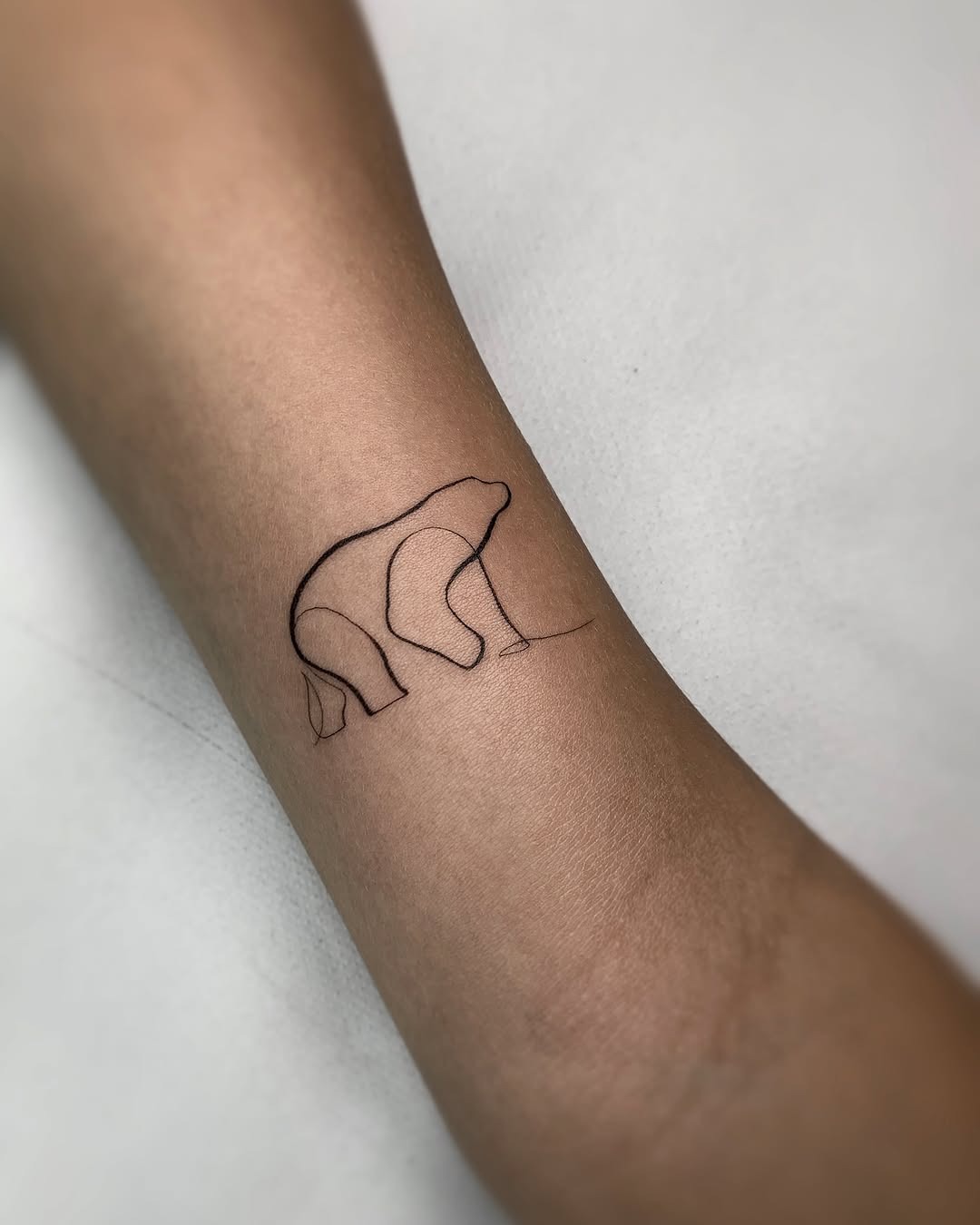 This tattoo showcases a sleek outline of a bear, emphasizing its graceful form.