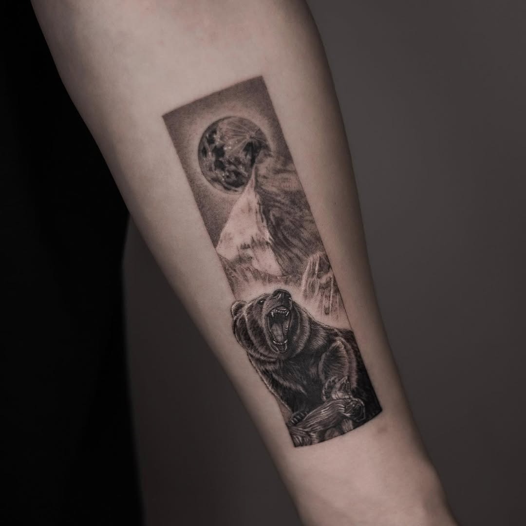 This tattoo features a roaring bear, symbolizing strength and courage, set against a stunning mountain backdrop.