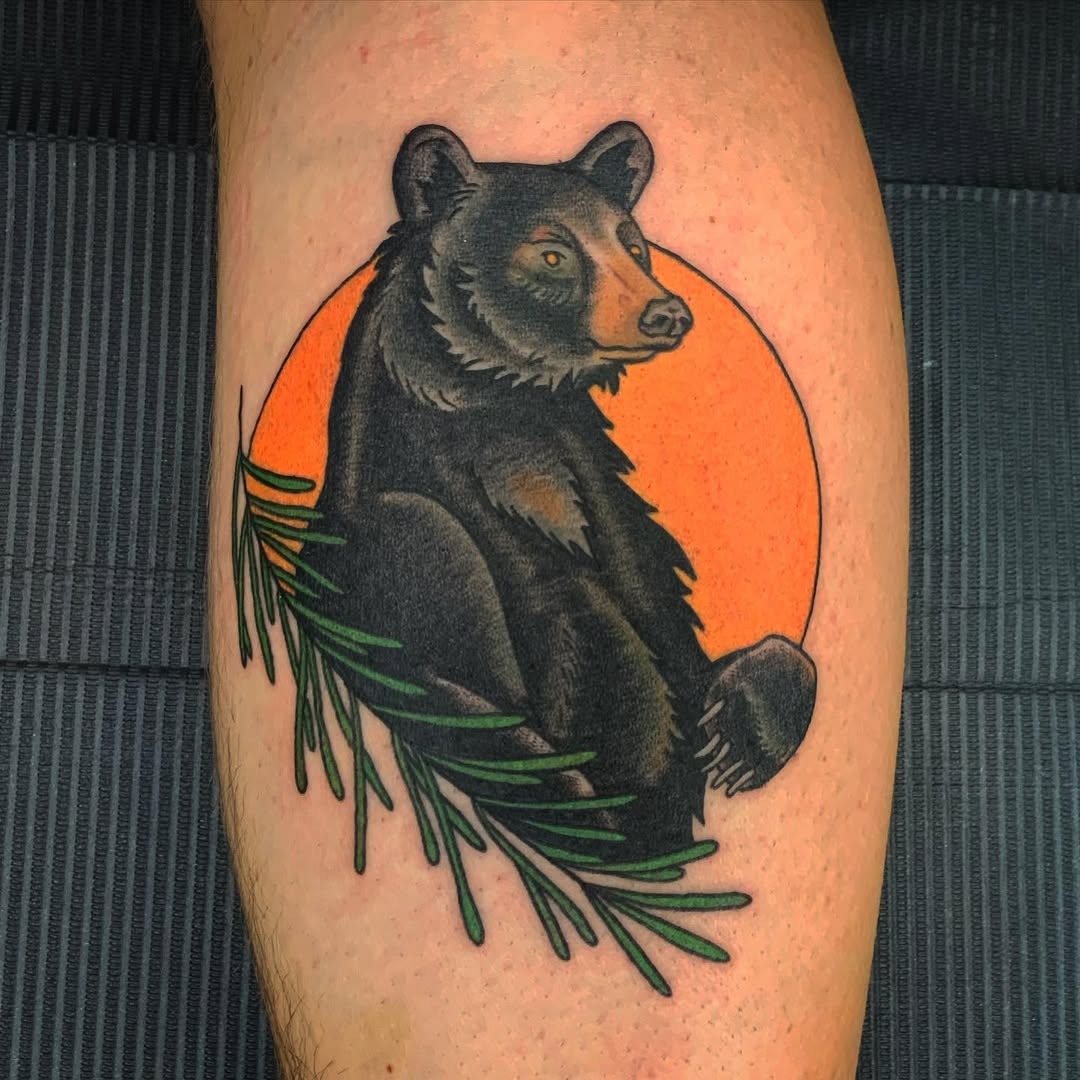 This striking bear tattoo features a majestic black bear set against a sunset orange background.
