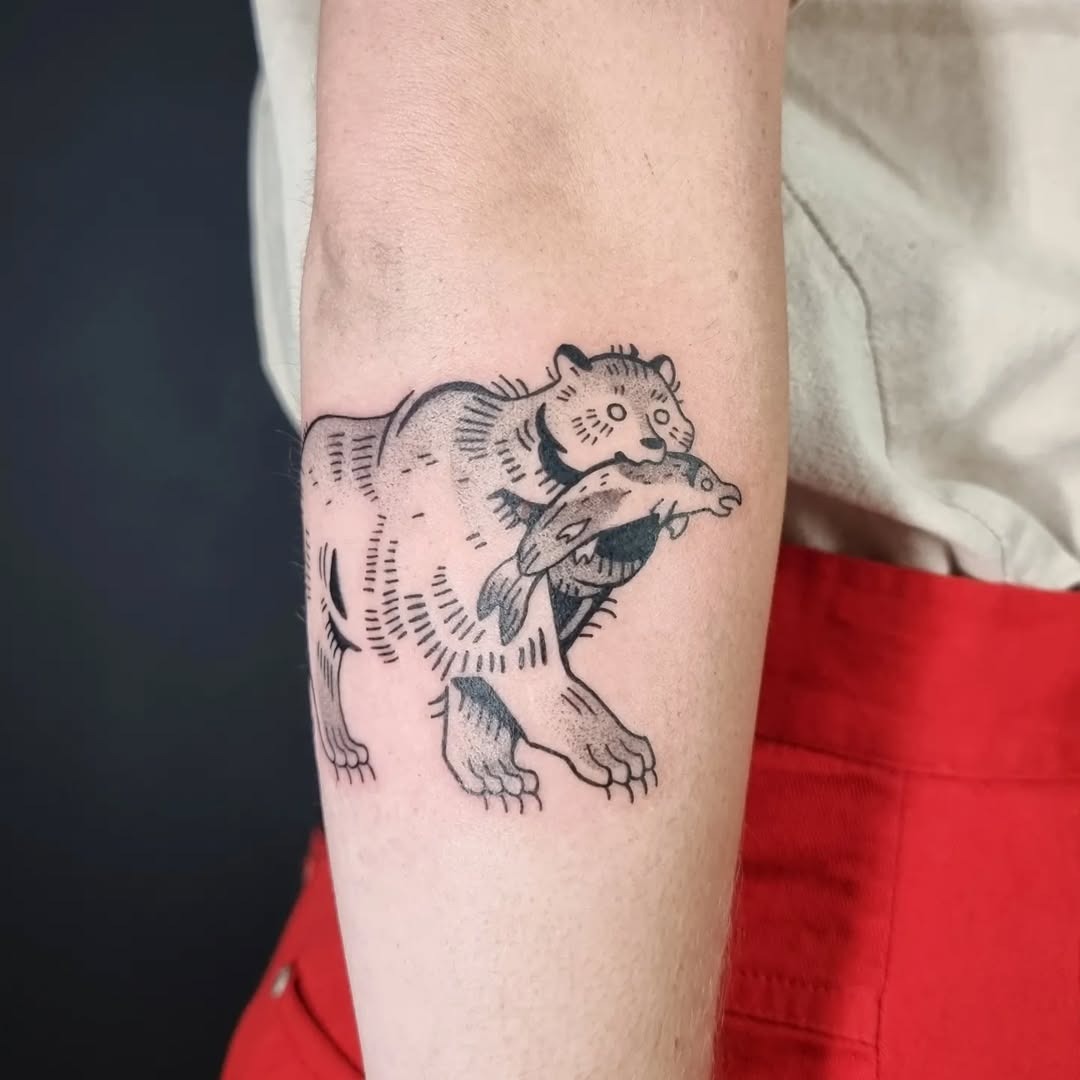 This tattoo features a bold bear grasping a fish, blending strength and nature beautifully.