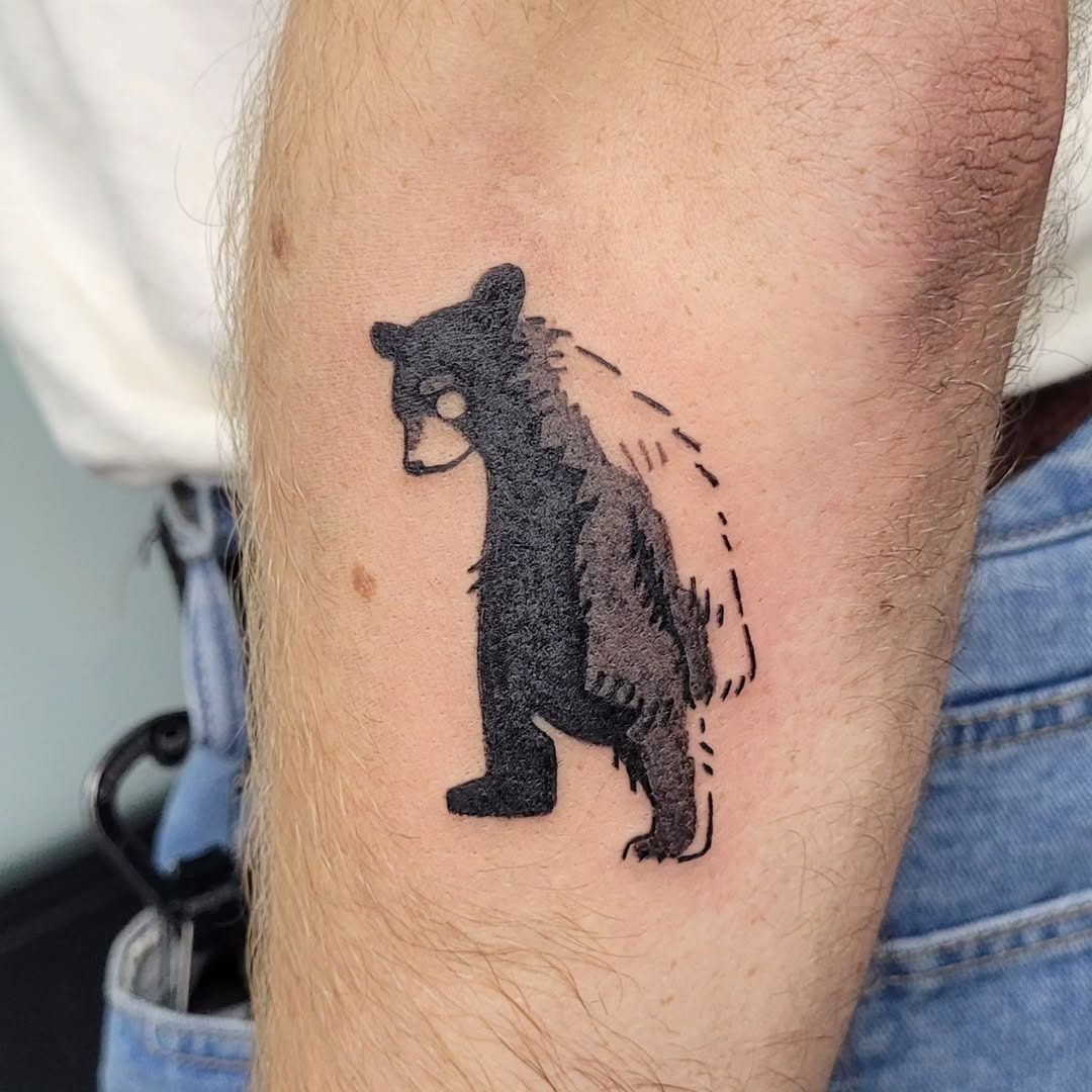 This tattoo depicts a minimalist bear, standing proud with simplistic lines and a black ink palette.