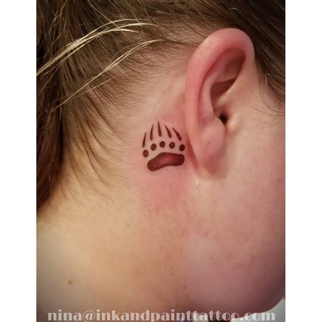 This bear paw tattoo is small and discreet, nestled right behind the ear.