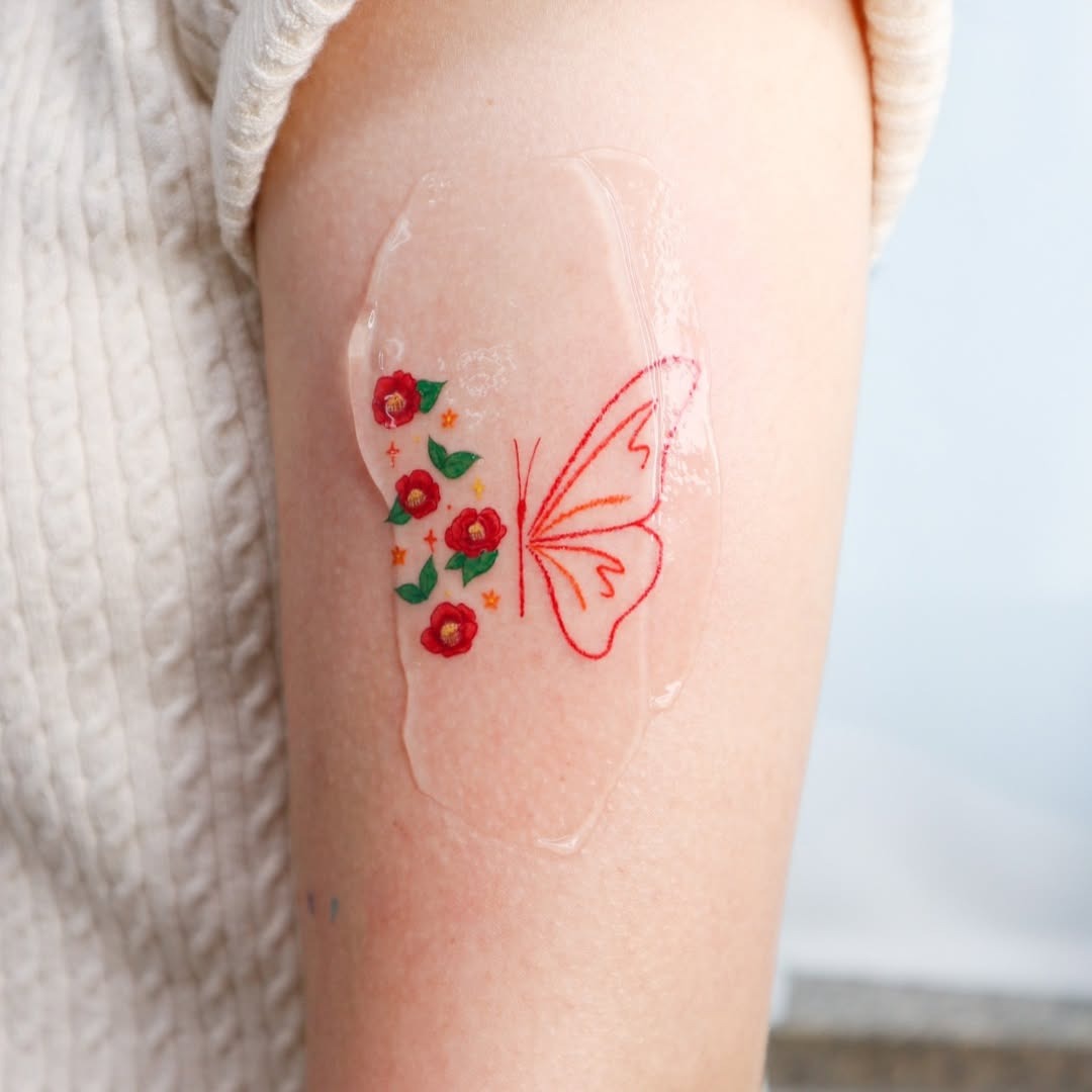 This butterfly tattoo features red flowers and delicate detailing.