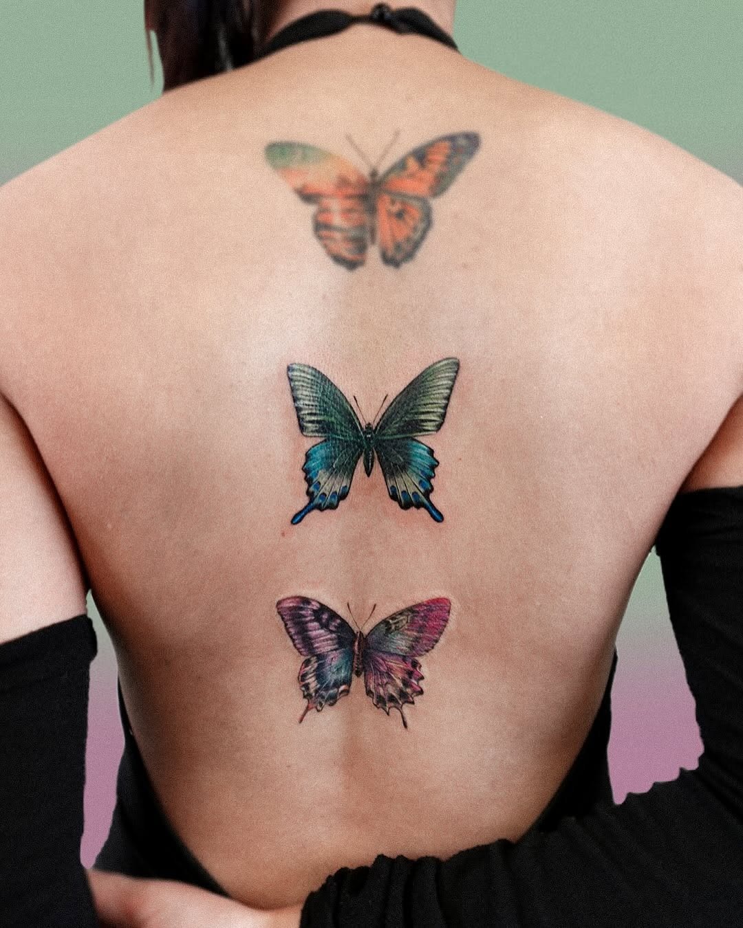 This image features a set of colorful butterfly tattoos elegantly placed on a person's back.
