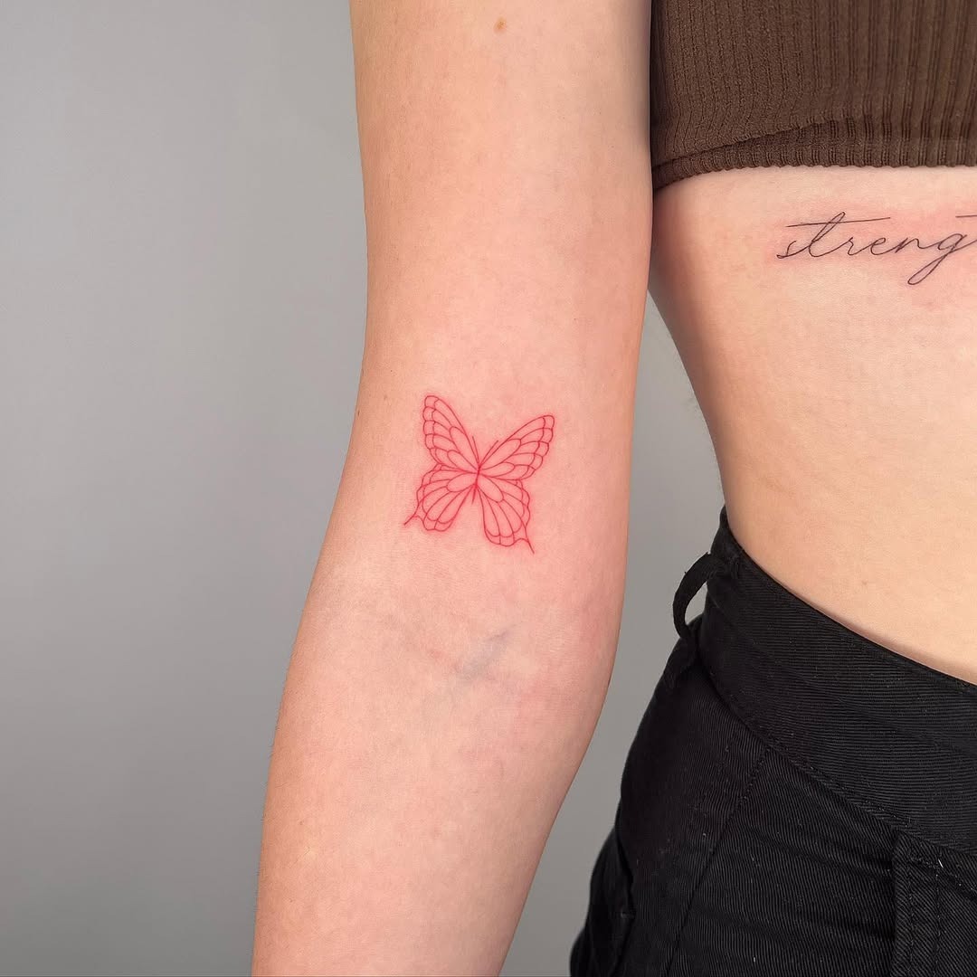 This charming butterfly tattoo features soft pink outlines that reflect a delicate aesthetic.