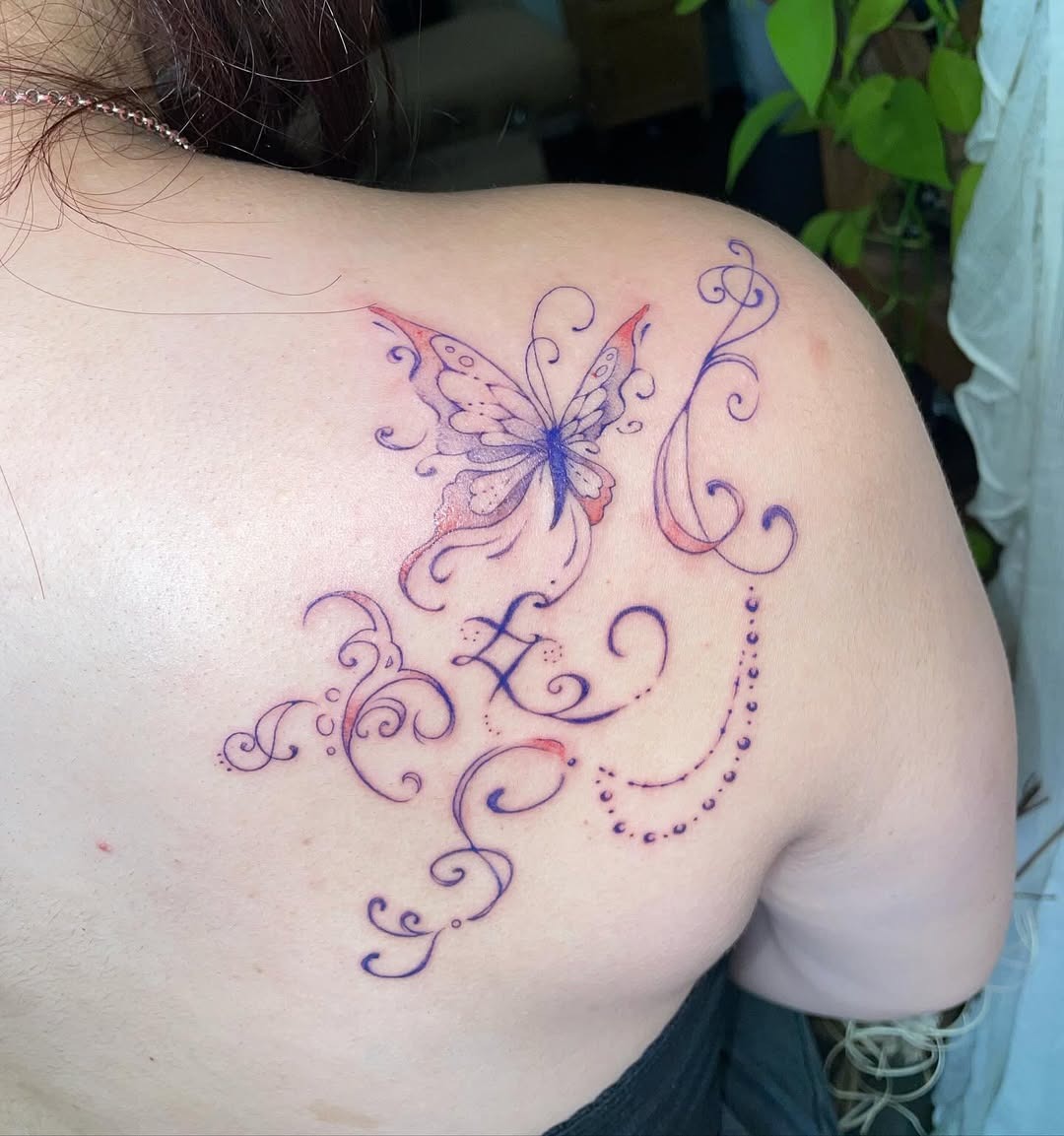This stunning tattoo features a butterfly perched amidst elegant swirls and flourishes.