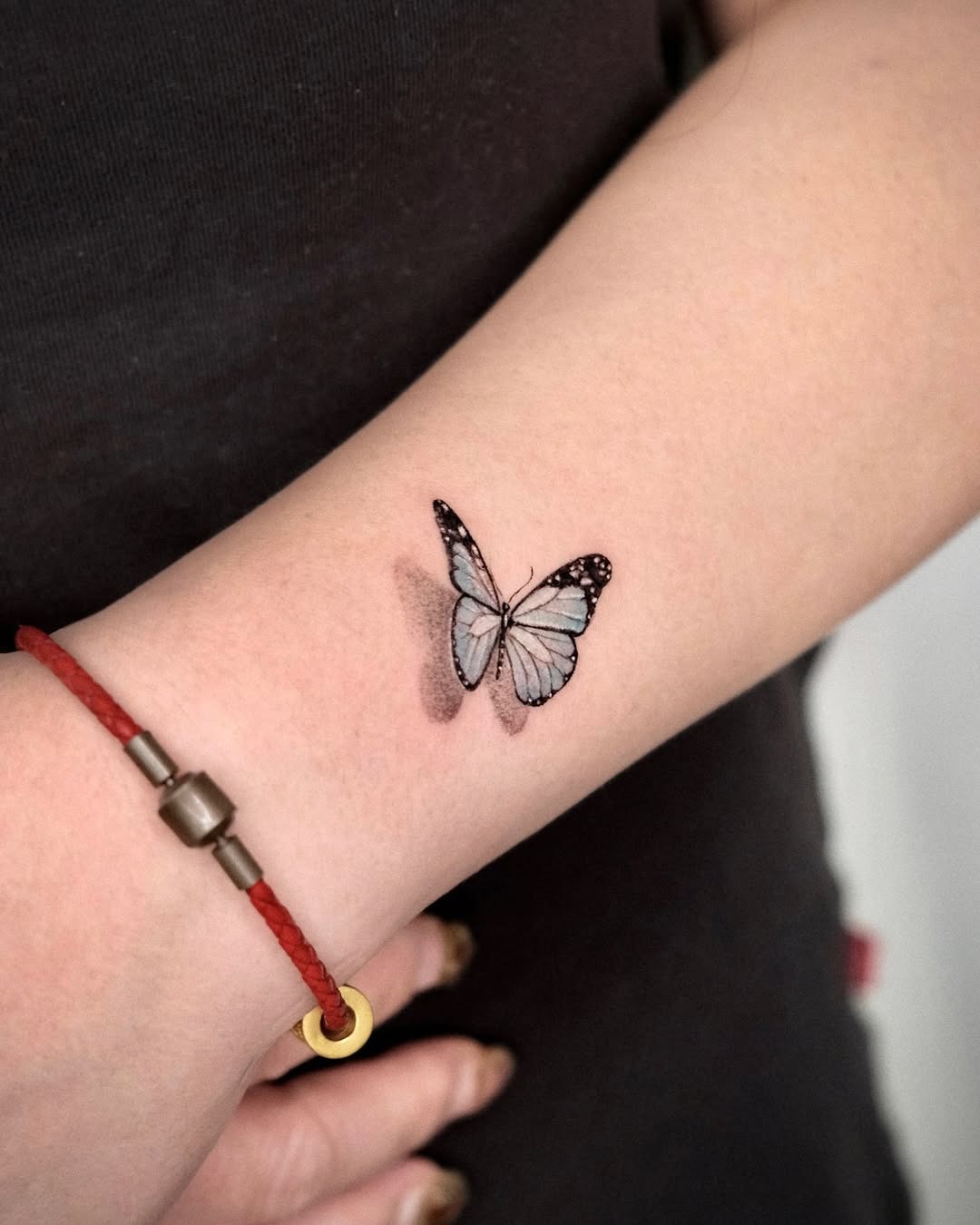 This butterfly tattoo features beautifully blended blue and black colors, creating a soft and elegant look.