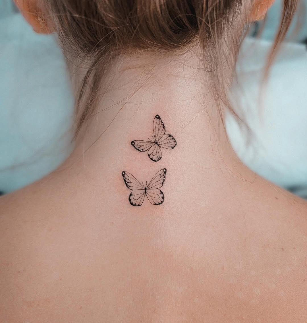 This image features two intricately designed butterfly tattoos located near the nape of the neck.