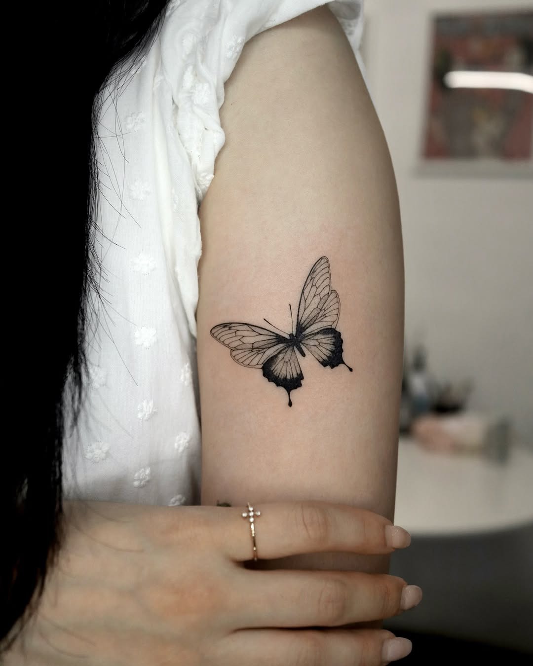 This tattoo features a beautifully detailed butterfly in black and white.