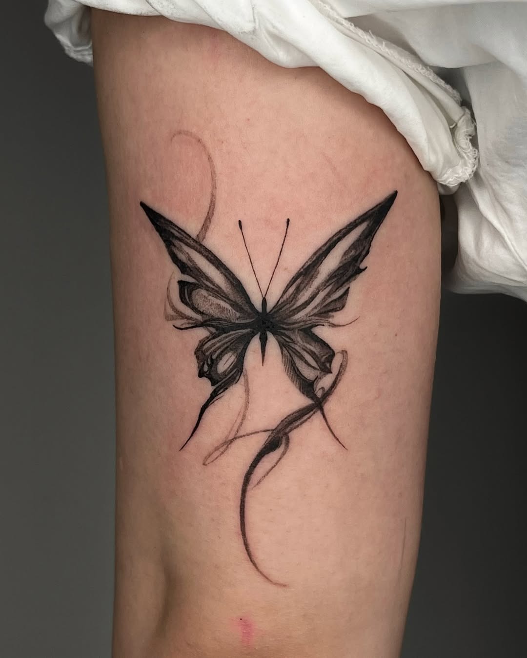 This stunning butterfly tattoo features intricate black detailing, creating a lifelike effect.