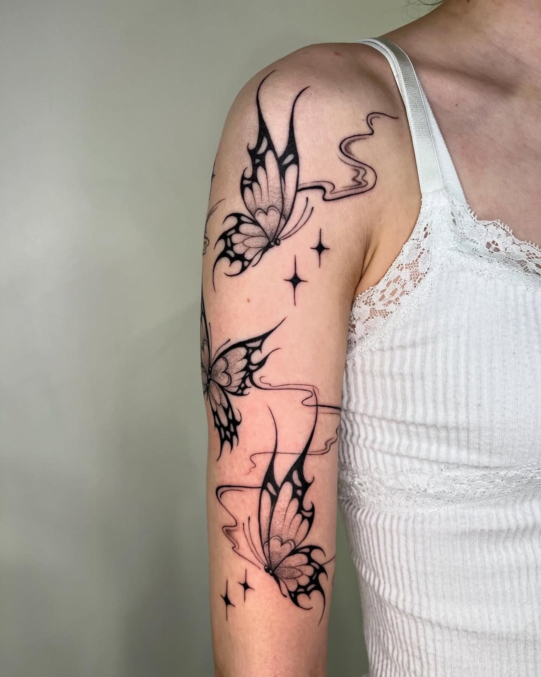 This minimalist butterfly tattoo features elegant black line art, showing three butterflies in flight.