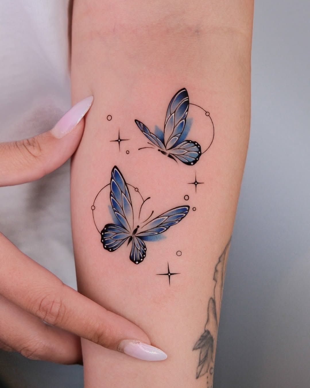 This tattoo features two beautifully designed blue butterflies that showcase intricate details and colors.