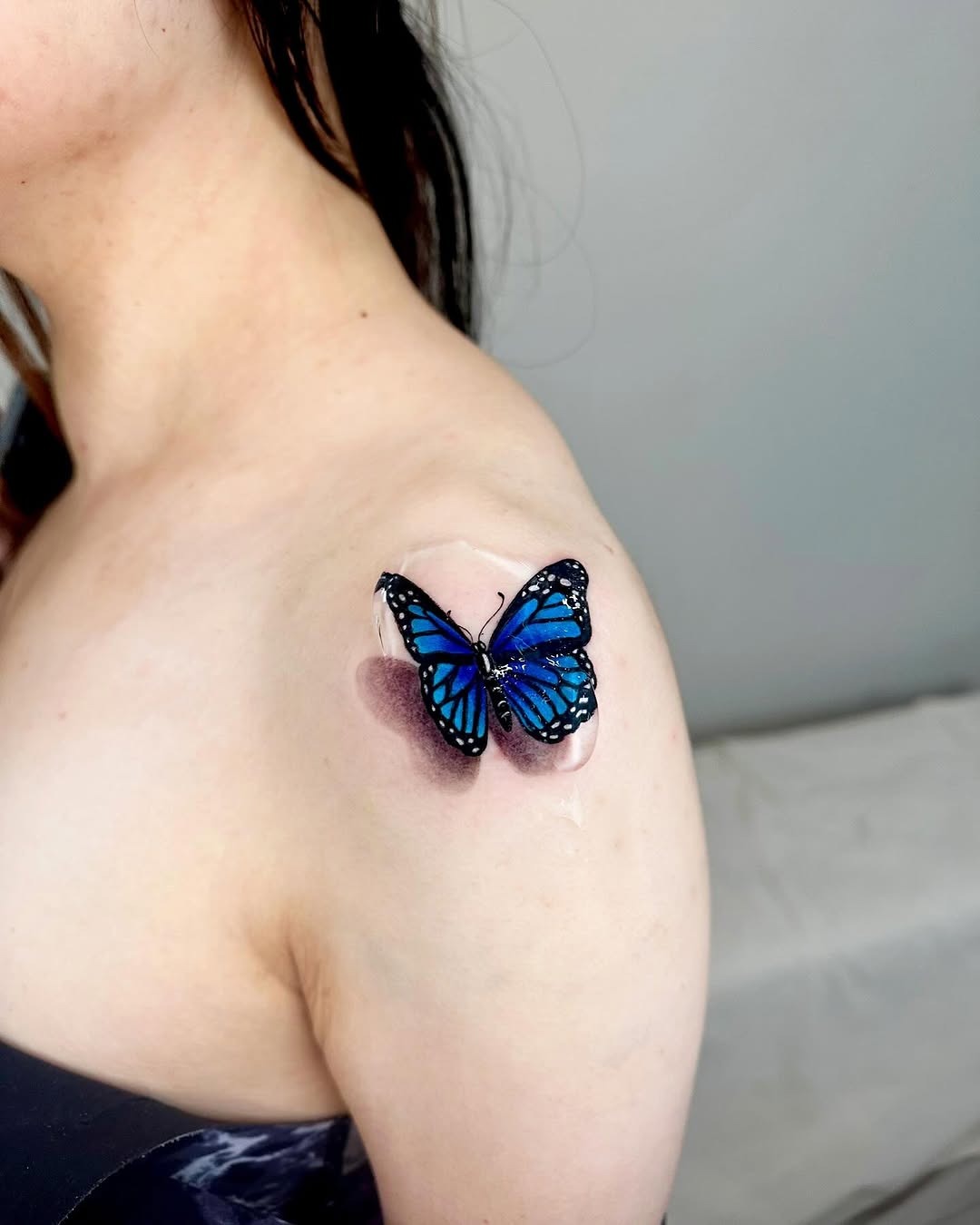 This stunning tattoo showcases a blue butterfly perched gracefully on the shoulder.
