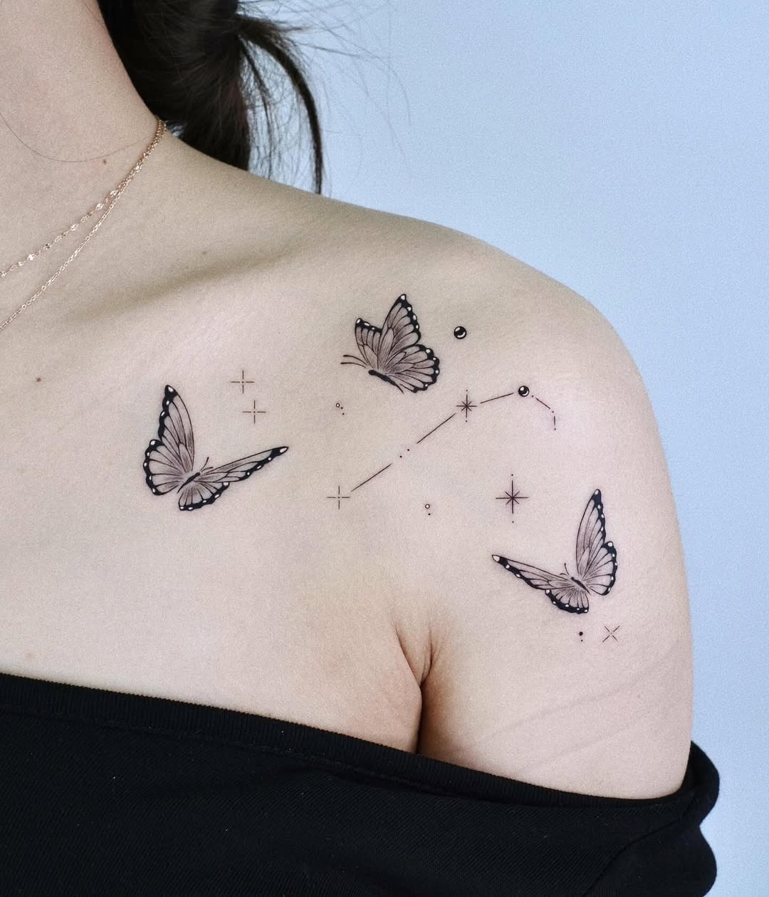 This stunning tattoo features delicate butterflies gracefully placed on the shoulder, intertwined with celestial stars.