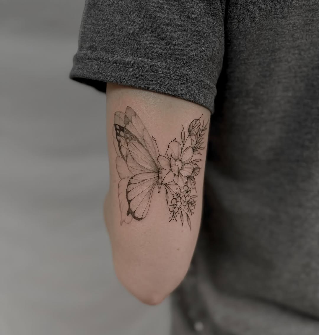 This stunning tattoo features a beautifully detailed butterfly intertwined with delicate flowers.